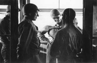 To the left, leaning on the doorframe, commander of the liberated camp of Gusen Lt. Col. Milton W. Keach, at the center, wearing sunglasses, his deputy Major Charles R. Sandler during a talk with former prisoners in Gusen. (photo credits: Courtesy of Maj. Charles R. Sandler, US 11th Armored Division, 21st Armored Infantry Battallion)
